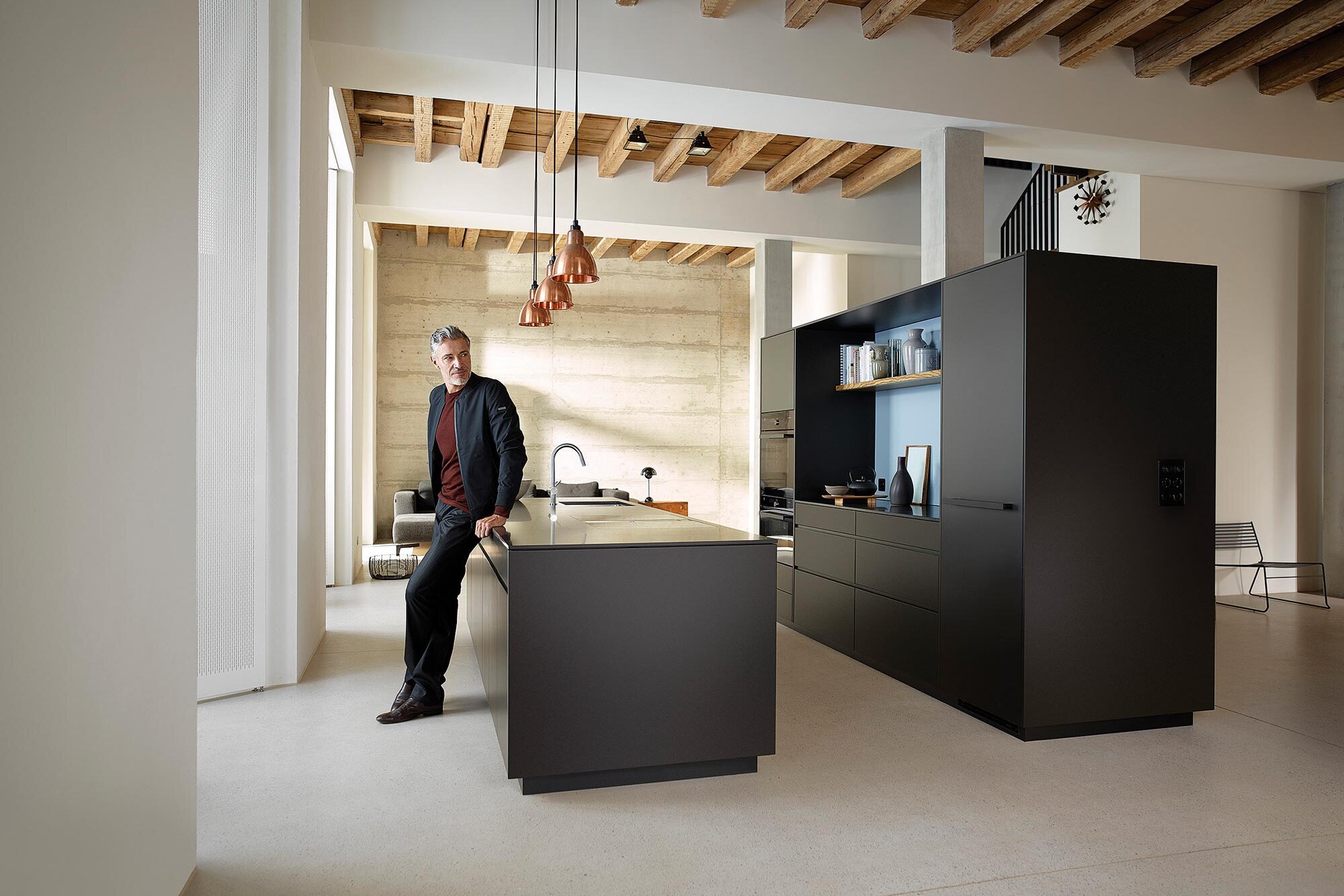 Muž opřený o ostrůvek v designové kuchyni v černé barvě
