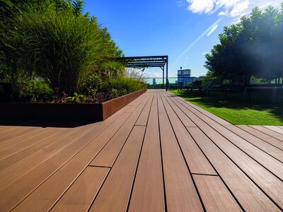 Při rozhodování mezi světlou a tmavou terasou byste měli vzít v úvahu nejen estetická hlediska, ale také praktická hlediska. Pohled na terasu v hnědé barvě v pozadí pergola